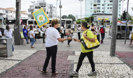 Funcionária da Funci entrega panfleto em praça